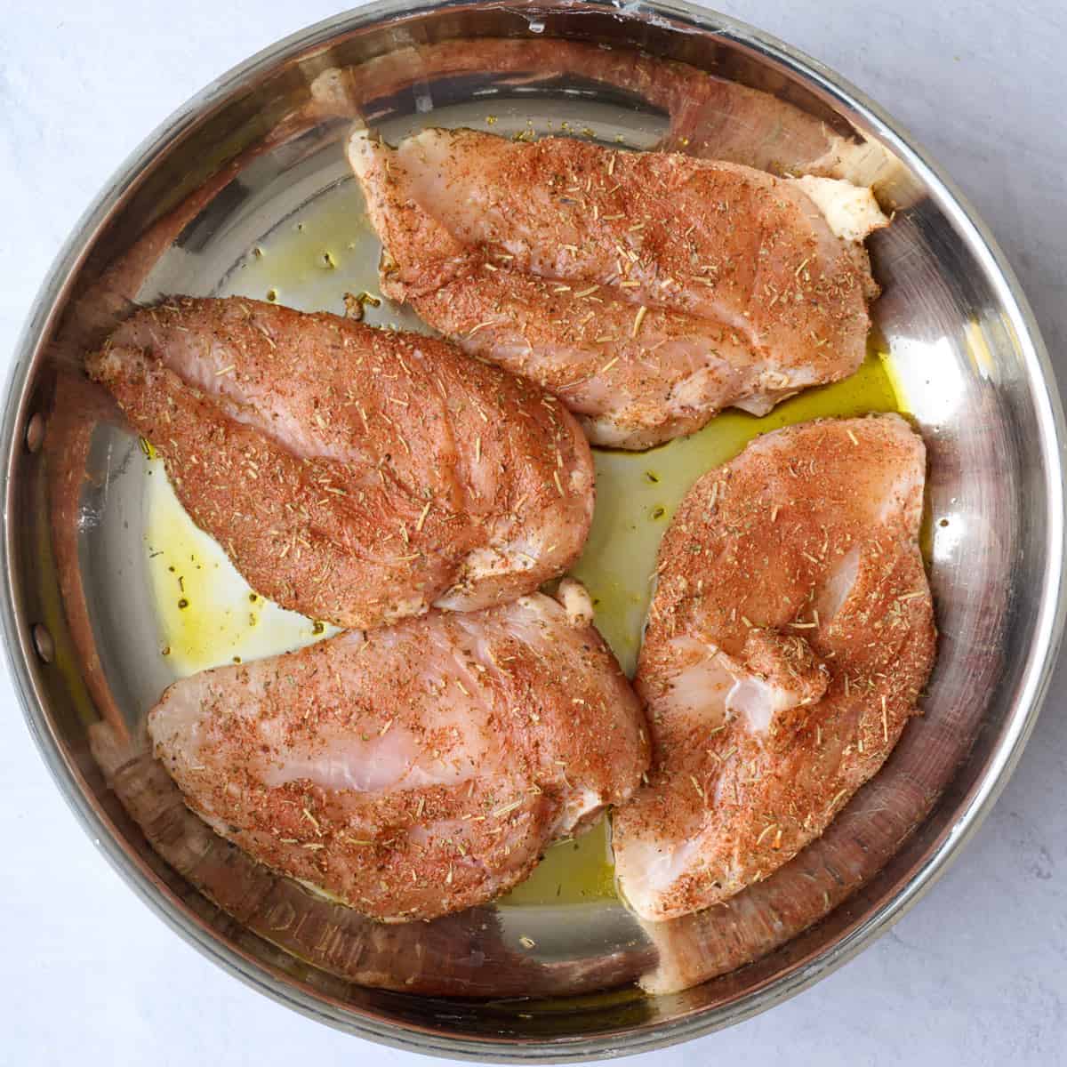 Seasoned chicken breasts in a skillet for marry me chicken recipe.