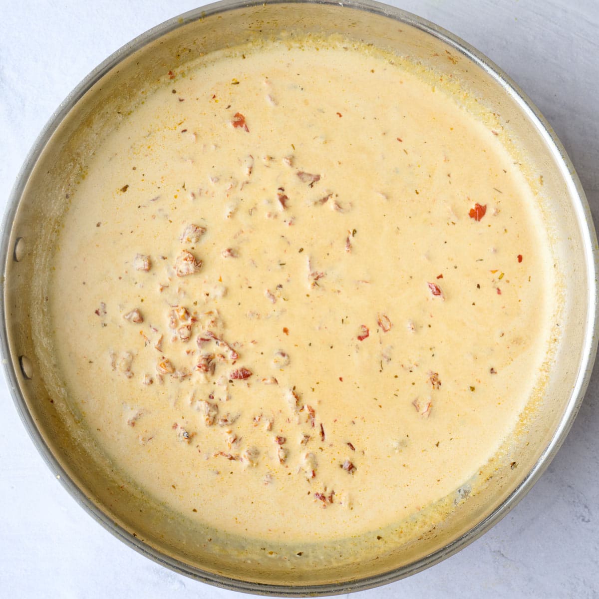 Creamy sun-dried tomato sauce after thickening in pan.