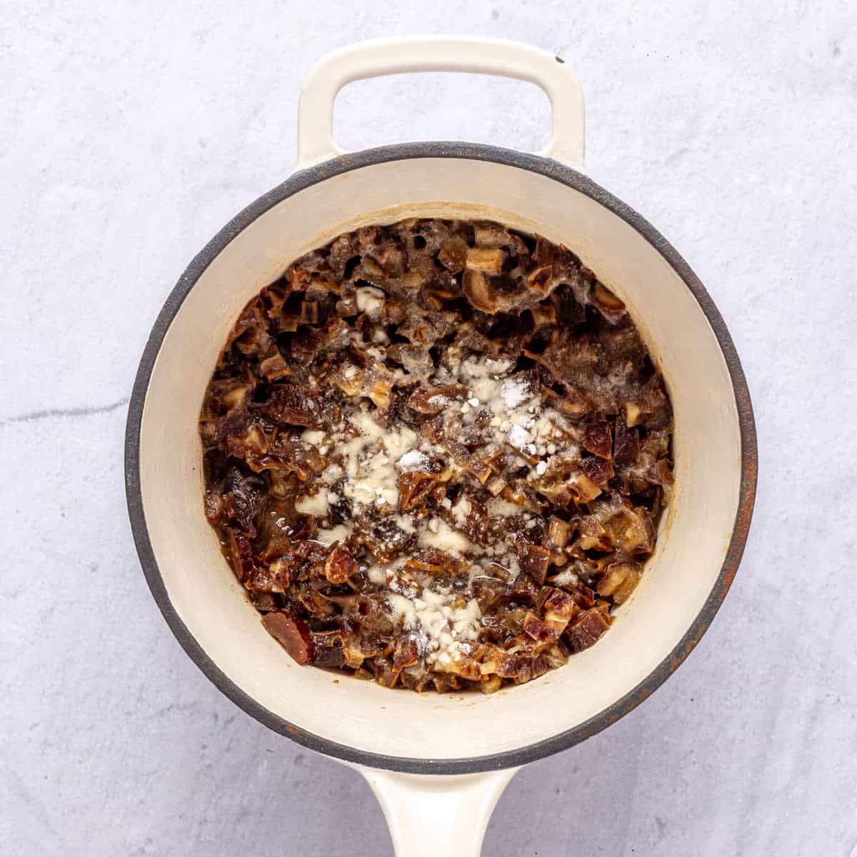 Dates and water after boiling in a small saucepan with baking soda sprinkled on top.