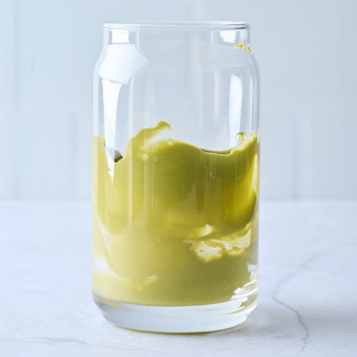Pistachio cream spread up the sides of a tall glass.