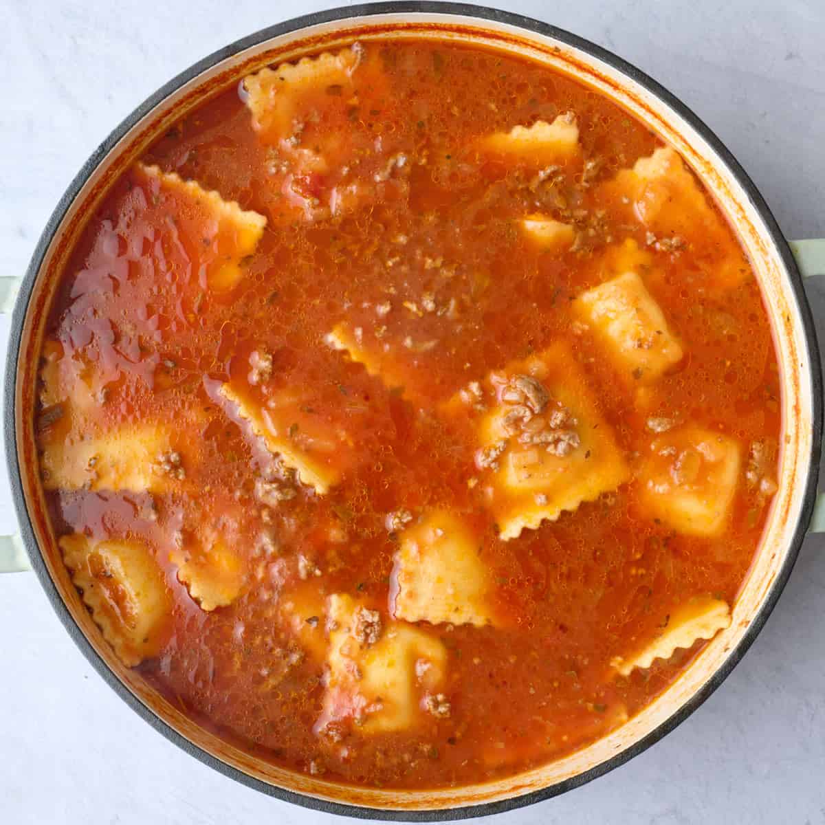Final pot of cooked ravioli soup showing the tomato broth, mini raviolis, and ground beef.