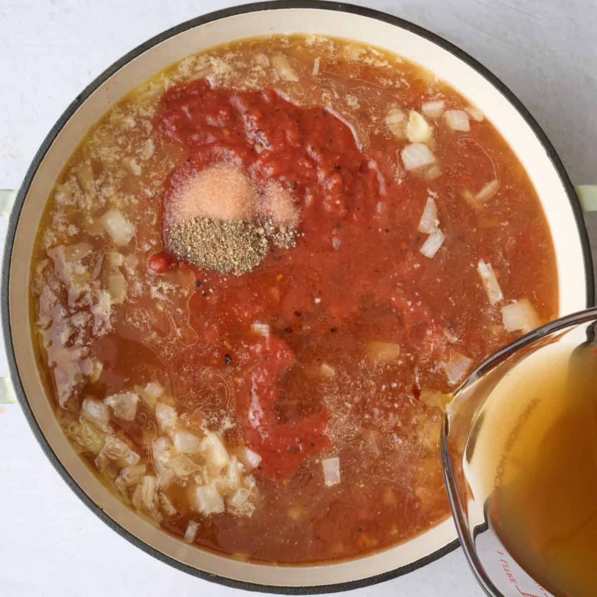 Crushed tomatoes, broth salt and pepper added to pot with onions and garlic.