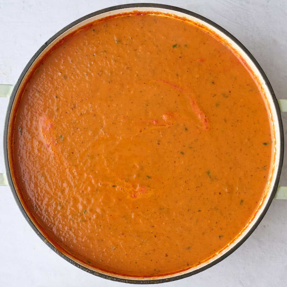 Creamy tomato soup recipe after blending smooth with specks of fresh basil throughout.