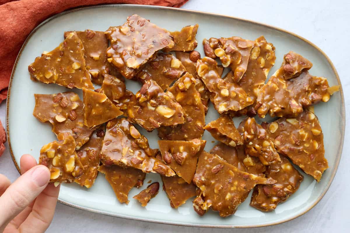 Almond brittle recipe without corn syrup broken into pieces on a platter.
