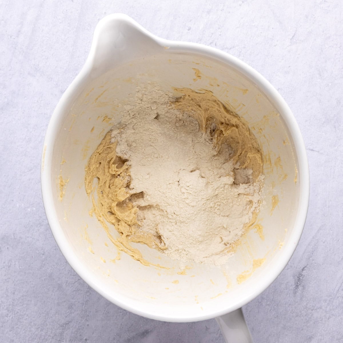 Cookie batter base with dry ingredients added on top before combining.