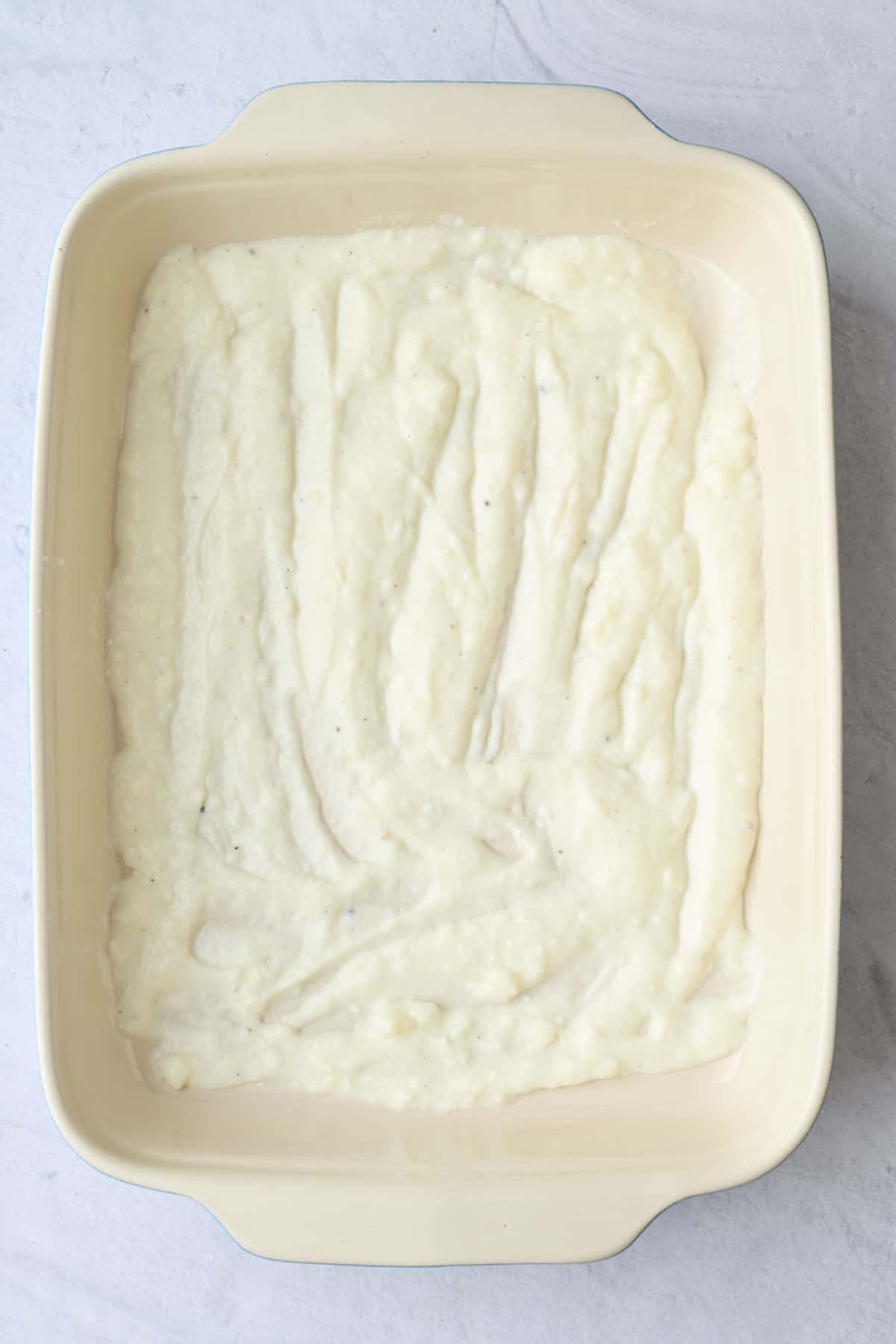 Bechamel sauce spread in the bottom of a baking dish for the first layer of lasanga.