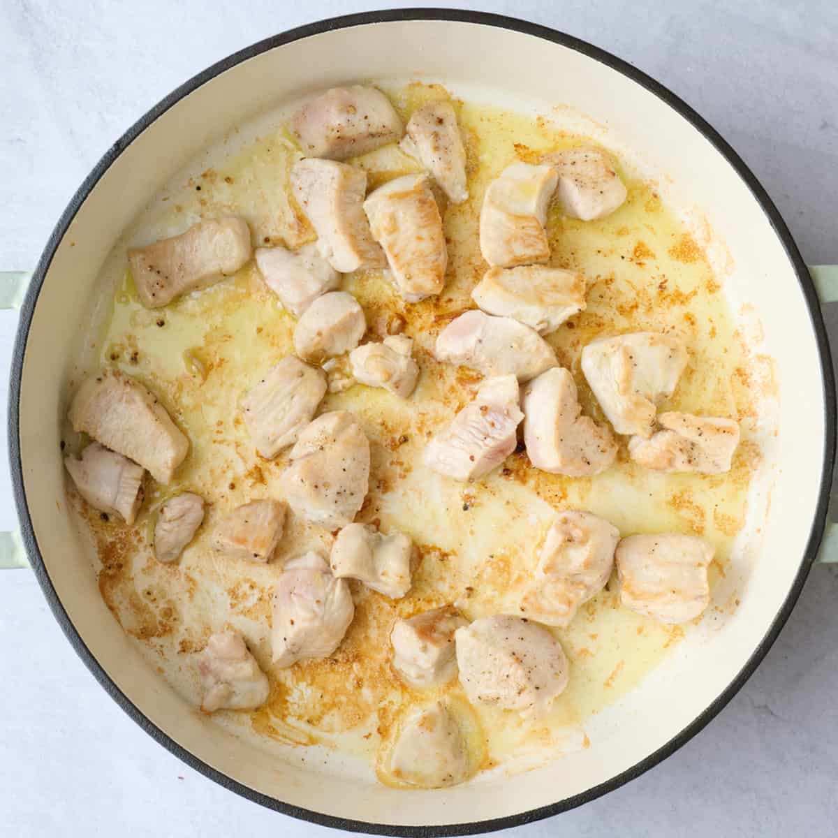 Seasoned chicken pieces in a pot with after cooking.