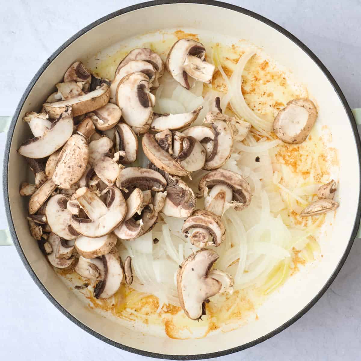 Sliced mushrooms and onions added to the same pot as the chicken after removing.