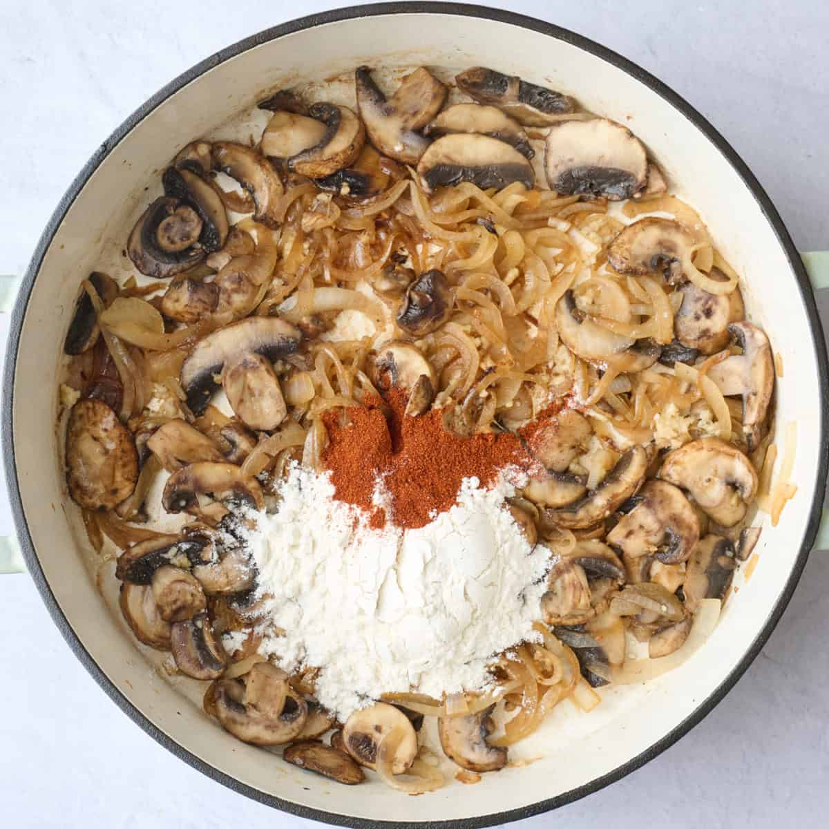 Sauteed mushrooms, onions and garlic with flour and paprika added on top before combining.