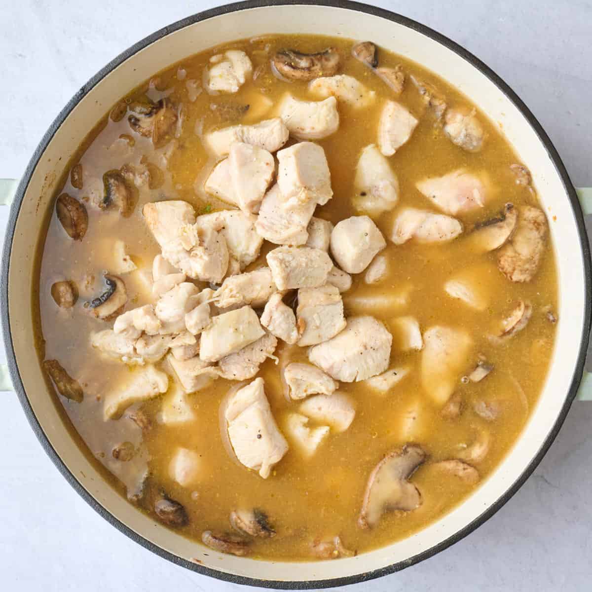 Chicken stock and dijon mixed in with chicken pieces and remaining salt added to pot.