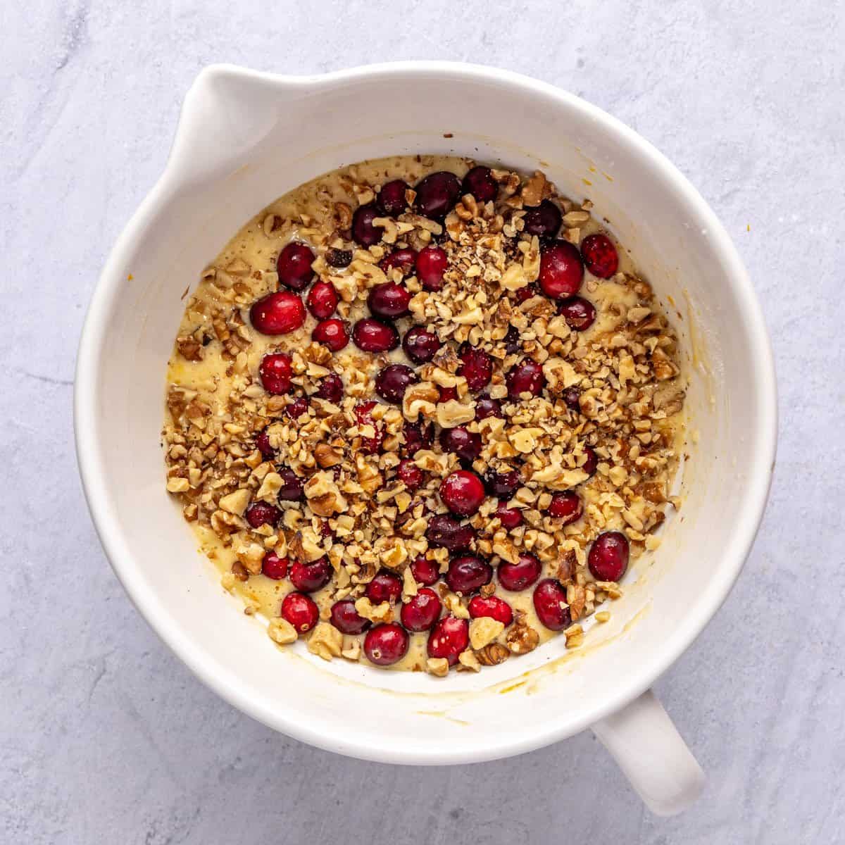 Quick dessert bread batter with cranberries and walnuts added on top before mixing in.