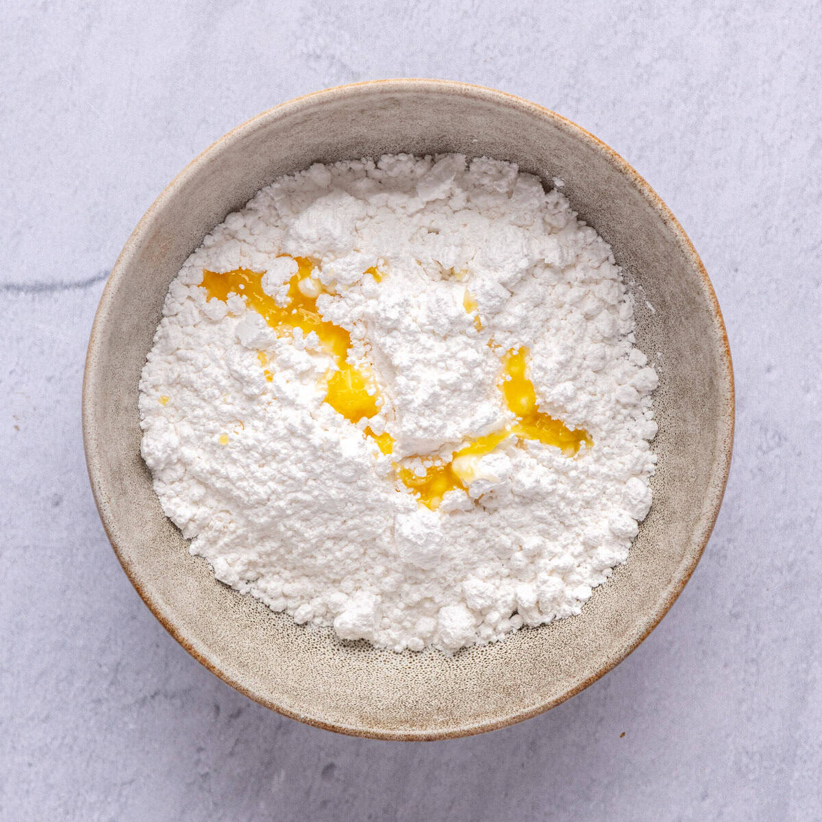 Powdered sugar and orange juice in a bowl before mixing.