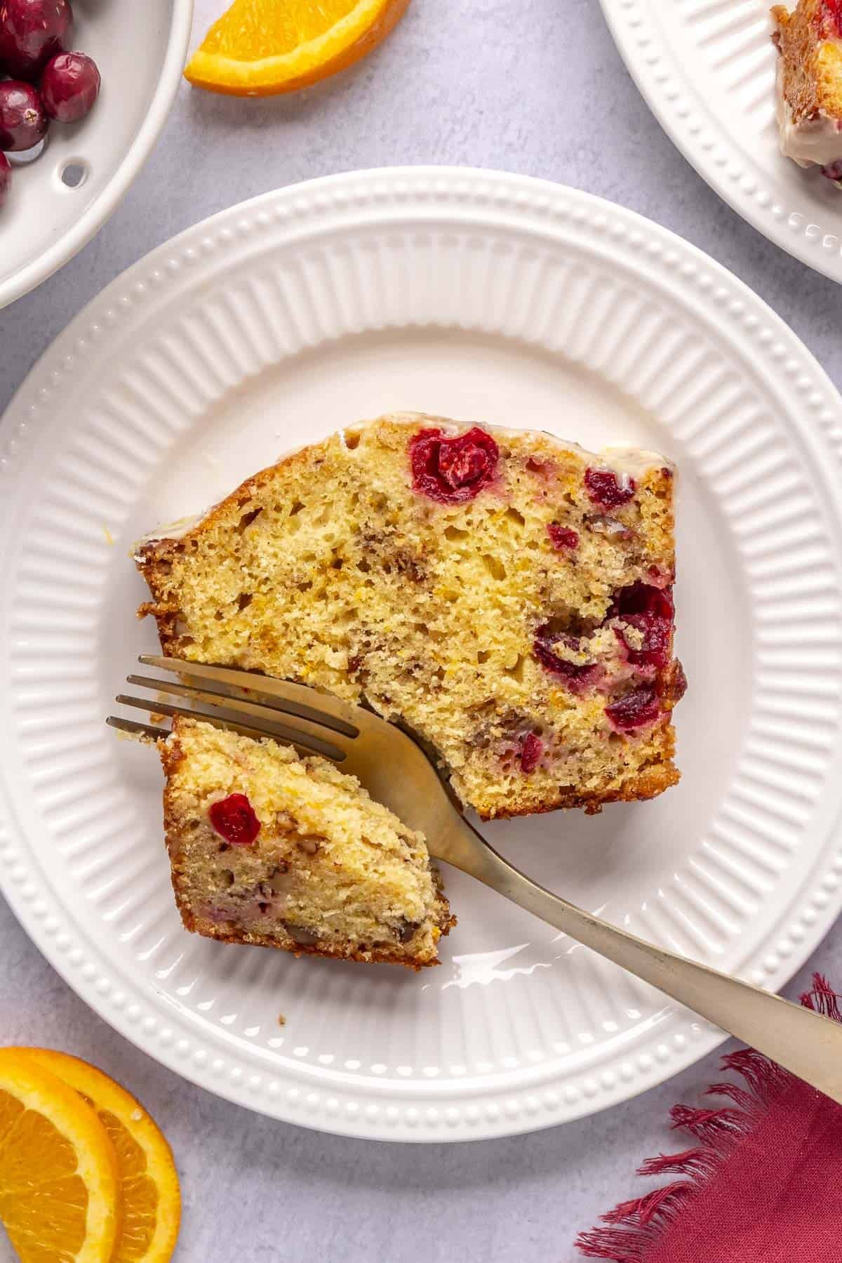 Slice of the best cranberry orange bread on a small plate with a fork breaking off a piece.