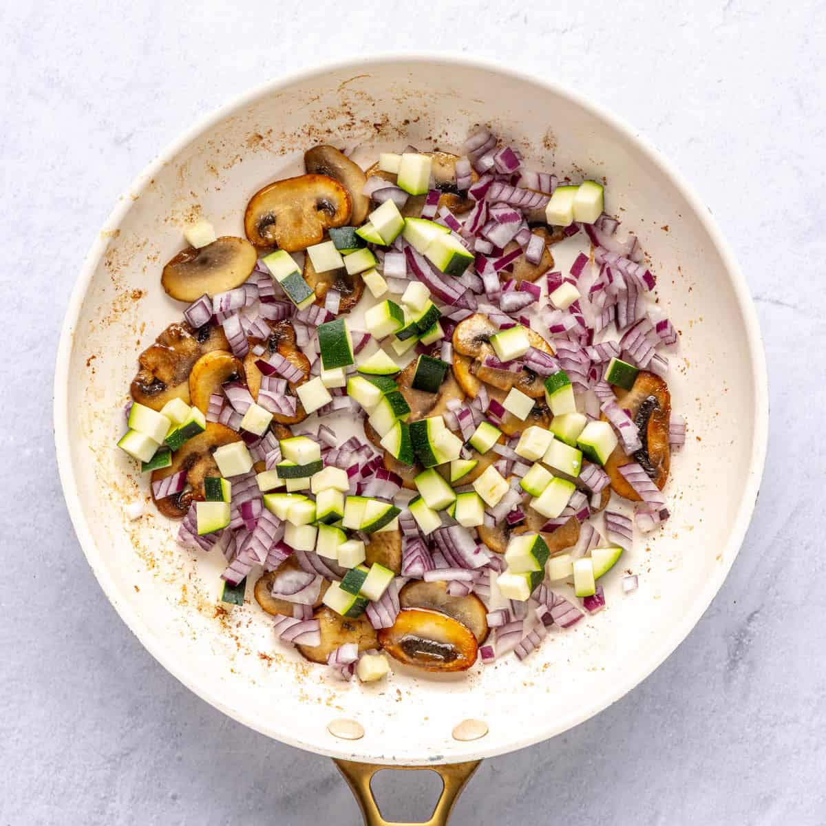 Mushrooms cooked in skillet, zucchini and onion added.
