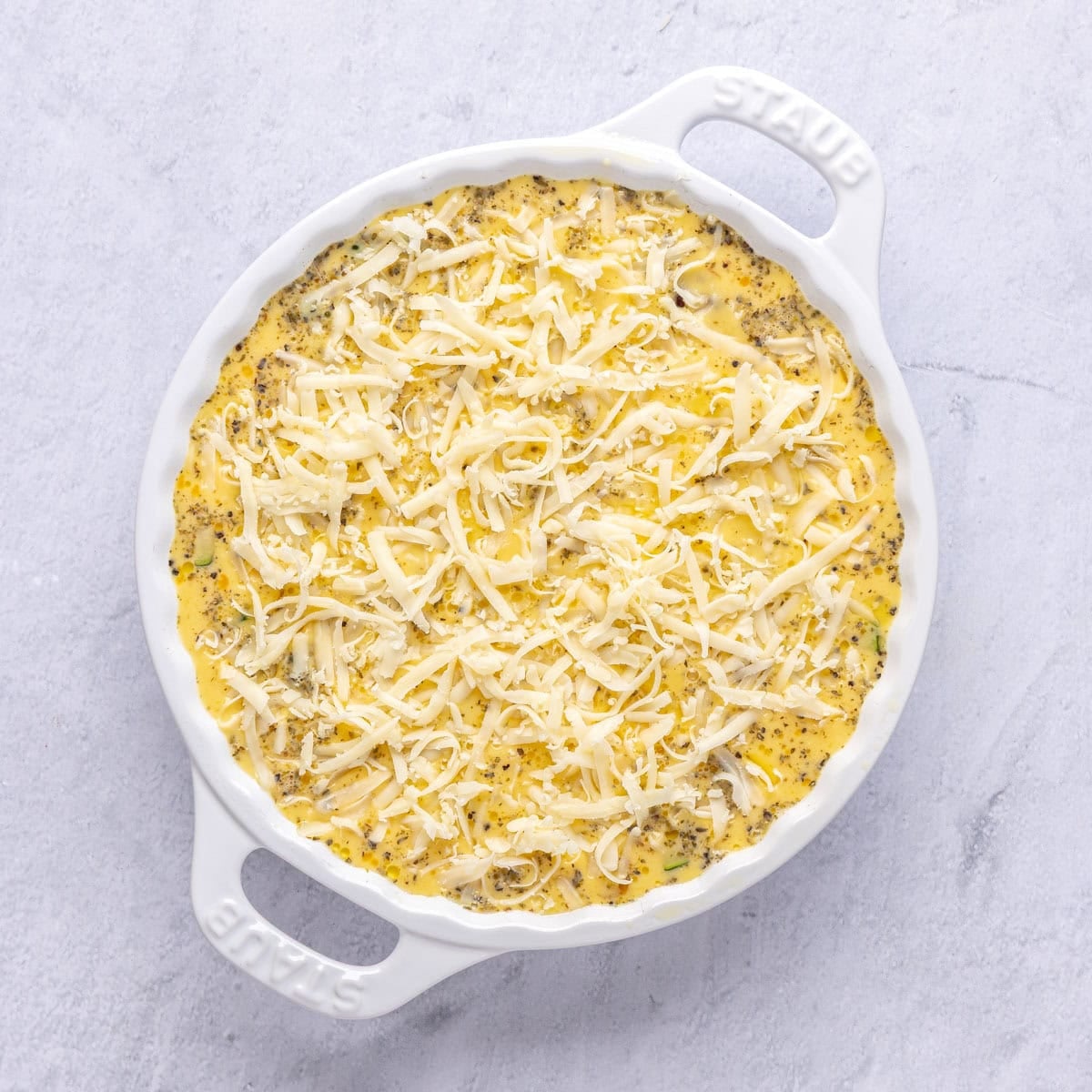 Eggs after whisked and poured on top of veggie cheese mixture with remaining cheese sprinkled on top for quich recipe before baking.