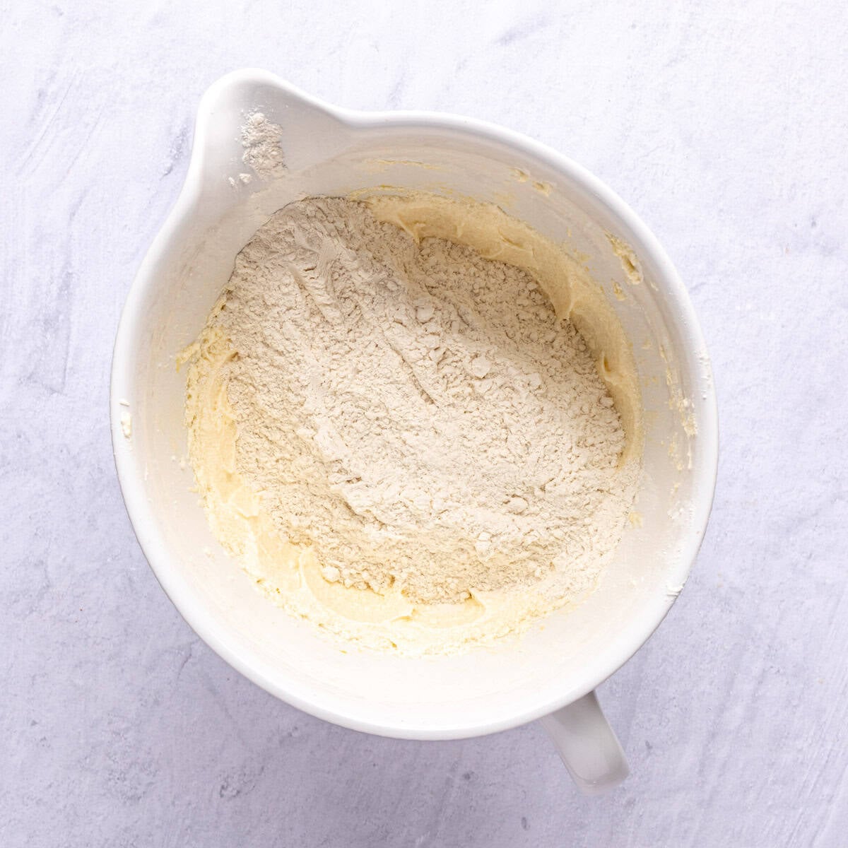 Flour and other dry ingredients added to wet cookie dough mixture before combining.