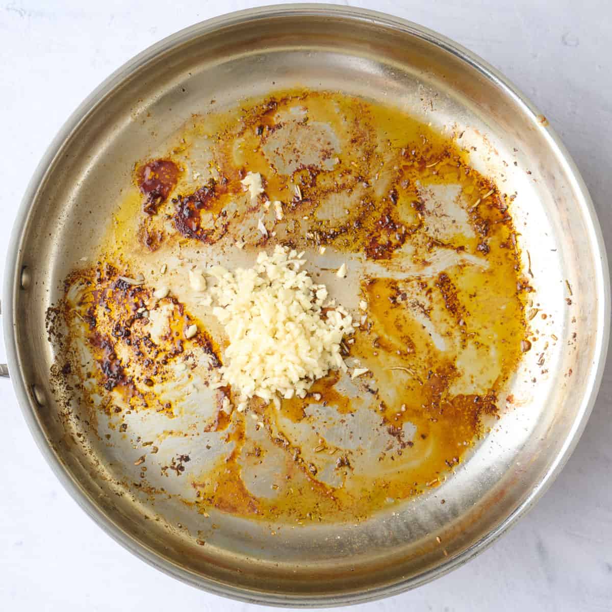 Garlic added to the same pan that chicken was cooked in before mixing with drippings.