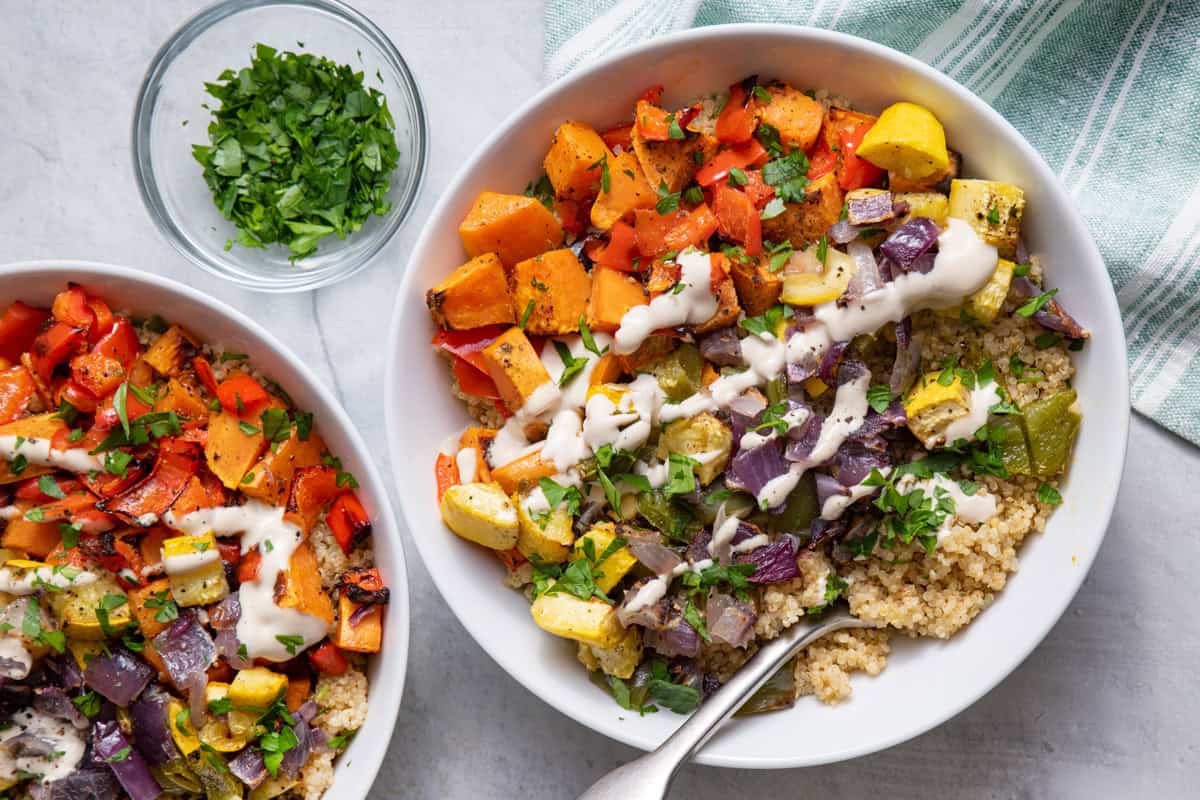 Roasted vegetable quinoa bowl topped with tahini sauce.