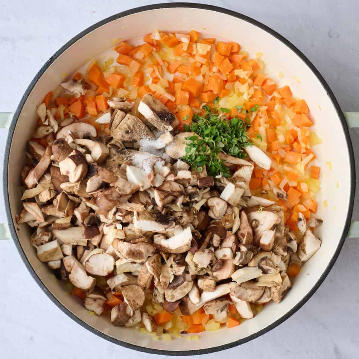 Mushrooms, thyme, salt and pepper added to pot with cooked onions and carrots before cooking.