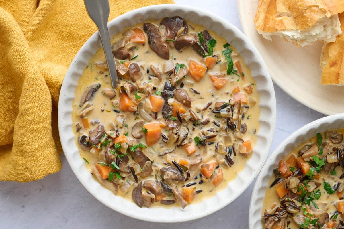 Homemade wild rice and mushroom soup recipe in a bowl with spoon dipped inside.