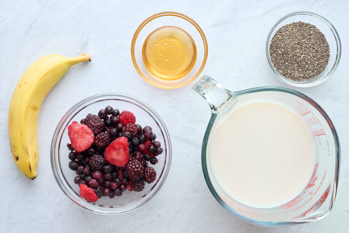 Ingredients for smoothie recipe: banana, frozen mixed berries, honey, milk, and chia seeds.