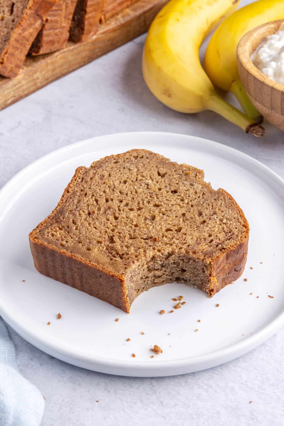 Slice of homemade cottage cheese banana bread on a plate with a bite taken out.
