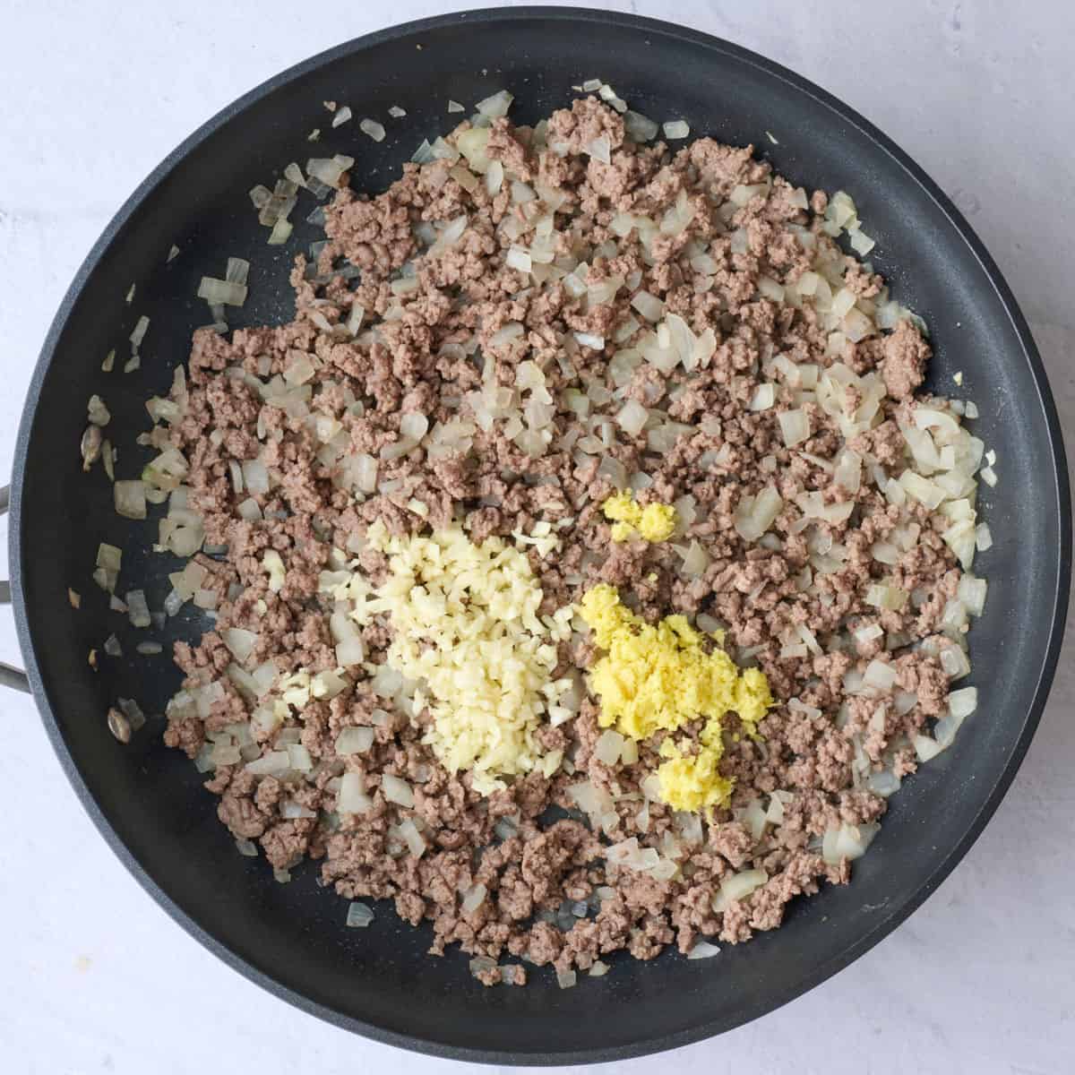 Ground beef after browning with garlic and ginger added before combining.