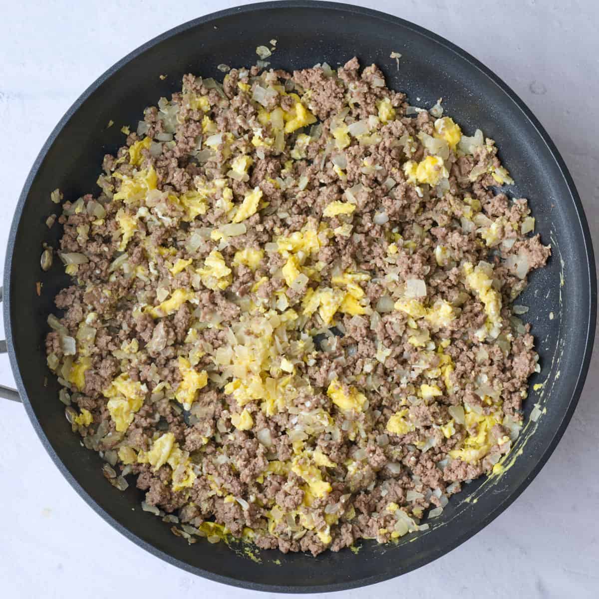 Eggs after scrambling and tossed with beef onion mixture for egg roll filling.