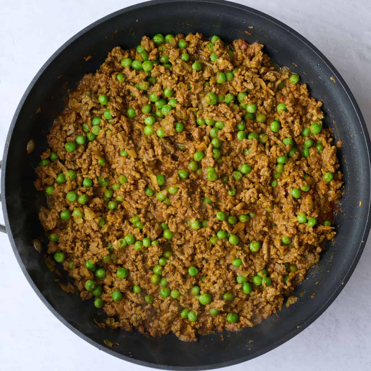 Curried ground beef and peas in a skillet.