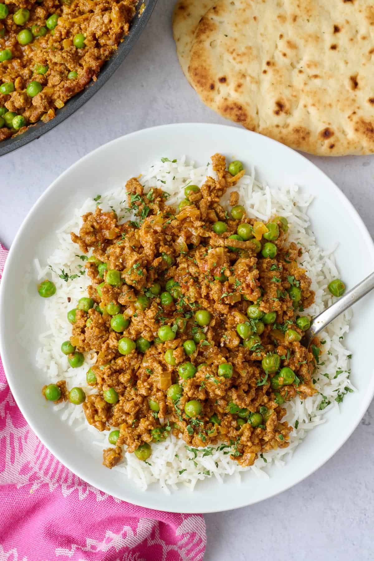 Easy keema curry recipe made with ground beef and peas served over white rice with naan nearby.