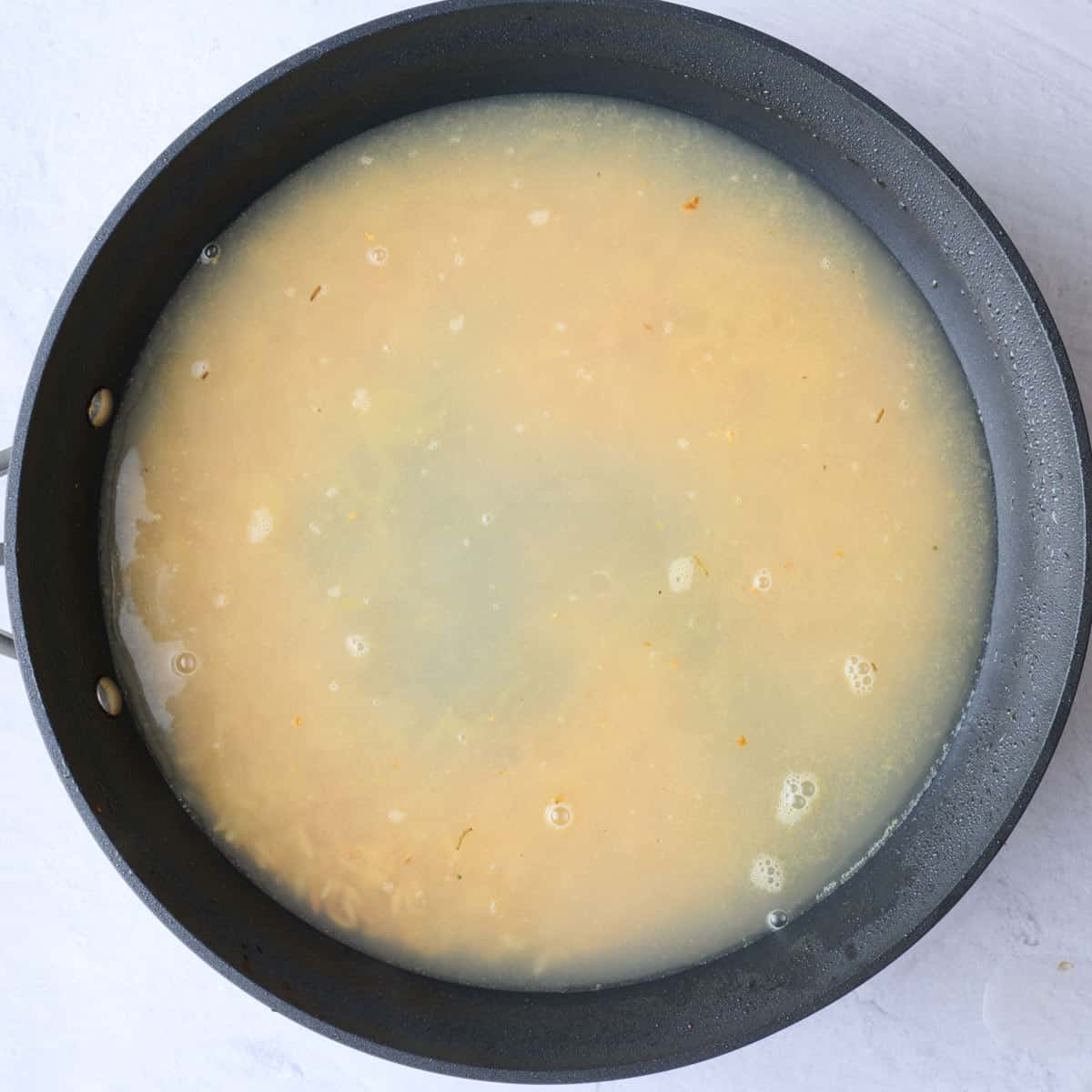 Chicken broth added to pan with toasted orzo.