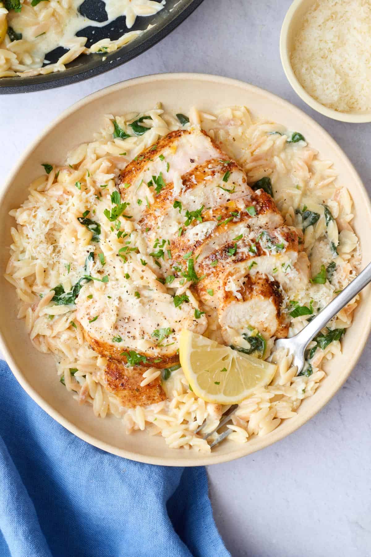 Serving of lemon orzo with sliced chicken breast on top.