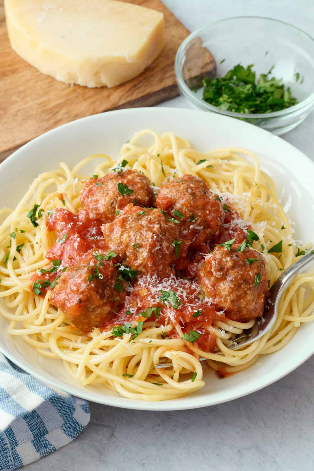 Homemade ground beef meatballs and spaghetti with marinara sauce garnished with parmesan cheese and parsley.