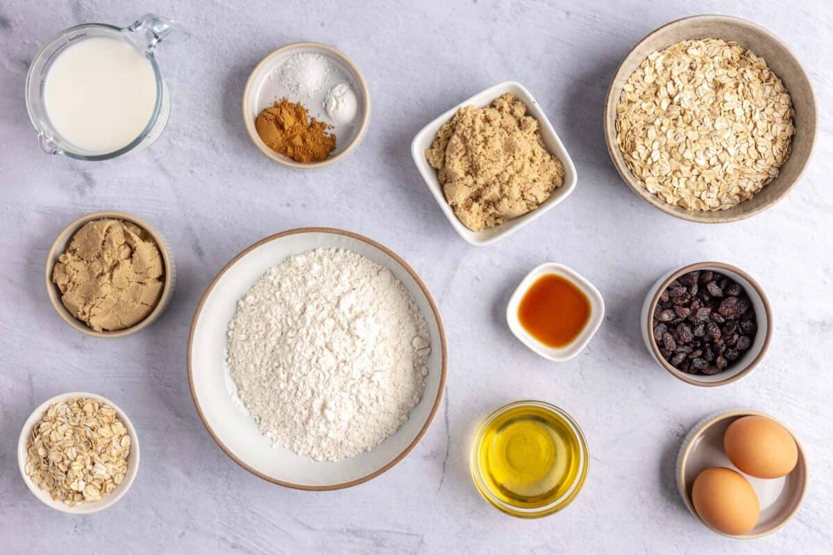 Ingredients for easy oatmeal muffins: milk, brown sugar, oats, flour, cinnamon, baking powder, salt, vanilla, oil, eggs, and raisins.