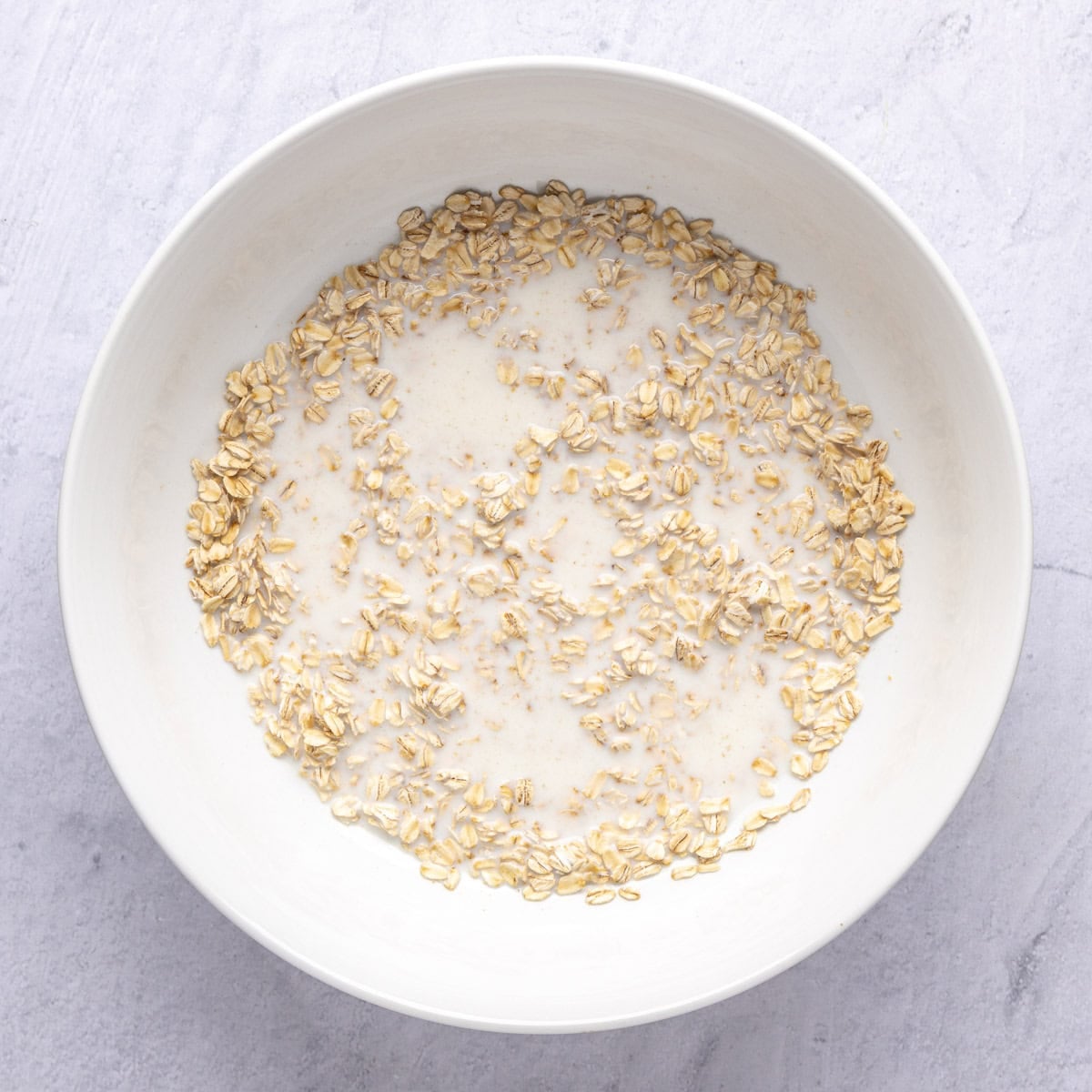 Oats and milk in a bowl before soaking.