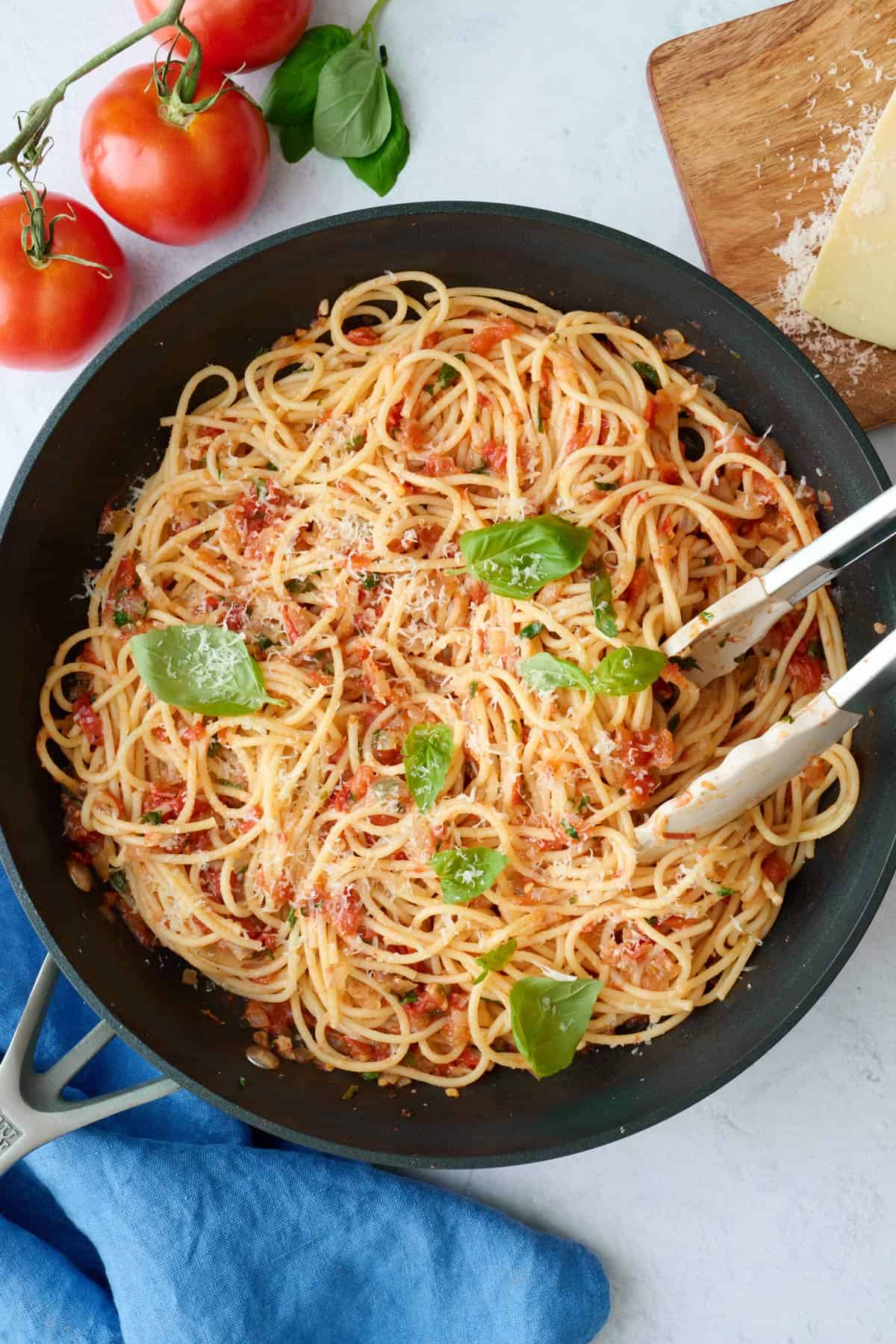 Best pasta pomodoro recipe serve in a skillet with freshly grated parmesan cheese and basil leaves on top.