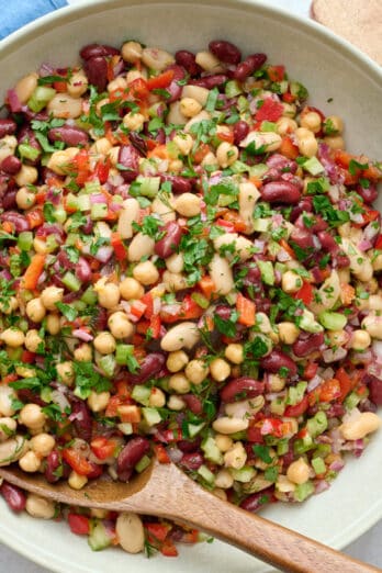 Best three bean salad in a serving dish with spoon dipped inside garnished with extra chopped parsley.