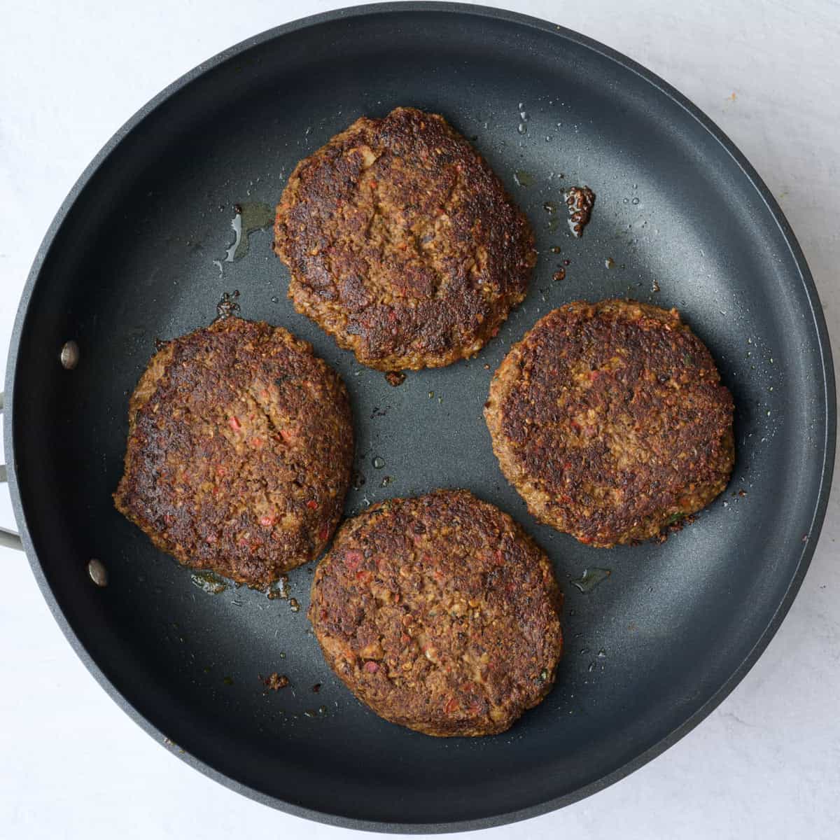 Veggie burger patties in a skillet after cooking.