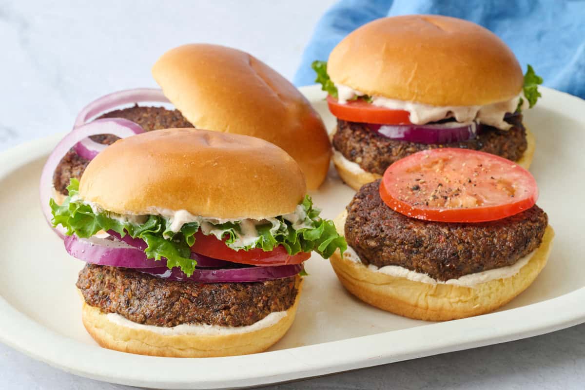 Easy veggie burger recipe made with black beans, mushrooms, and walnuts assembled on buns with toppings.