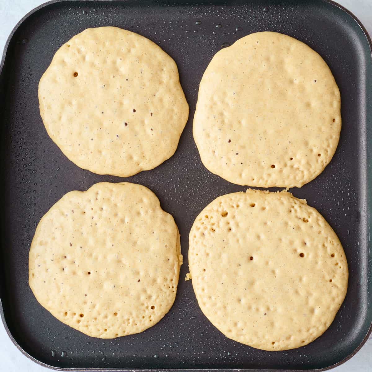 4 wheat pancakes on a hot griddle before flipping.