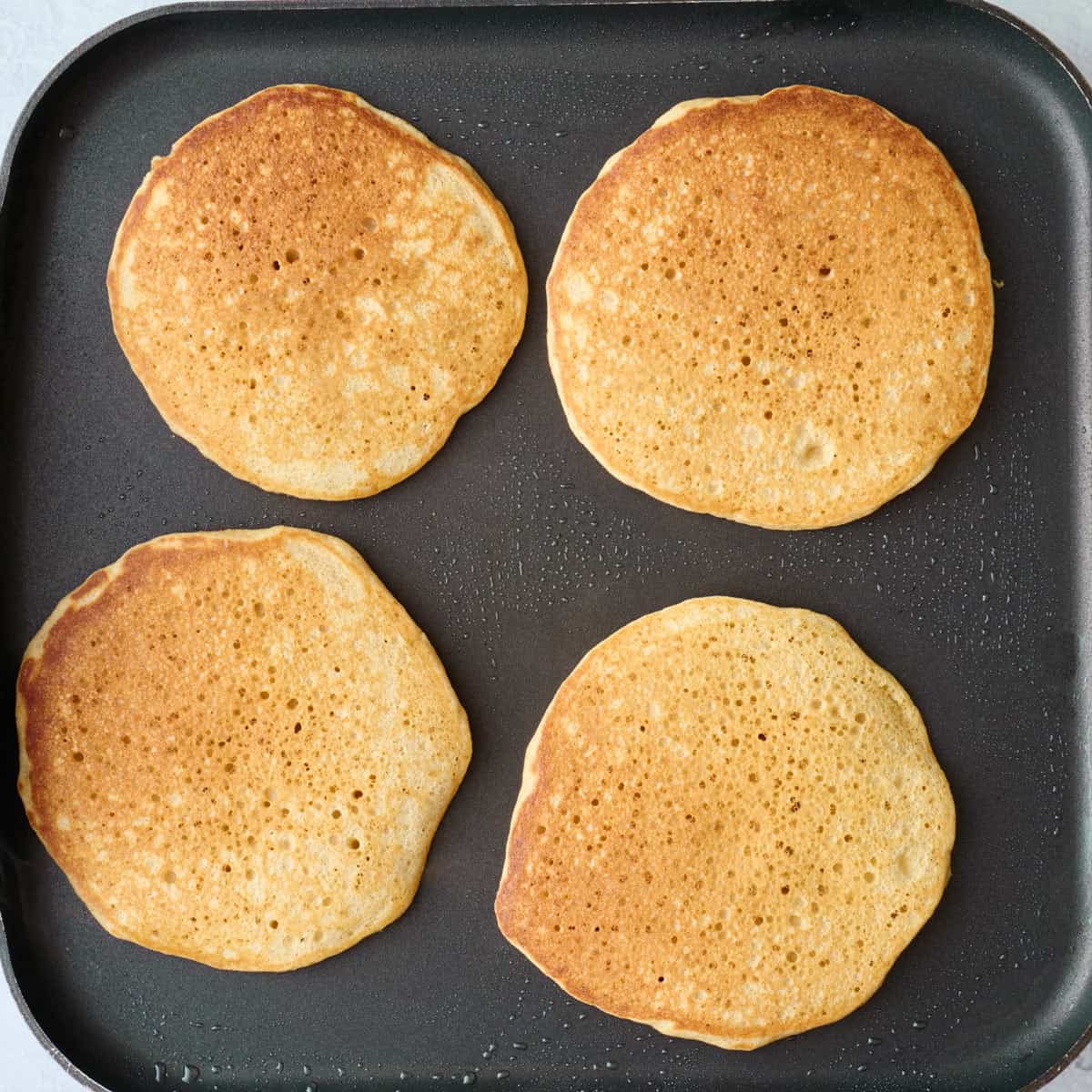 Pancakes after flipping to show golden brown top.