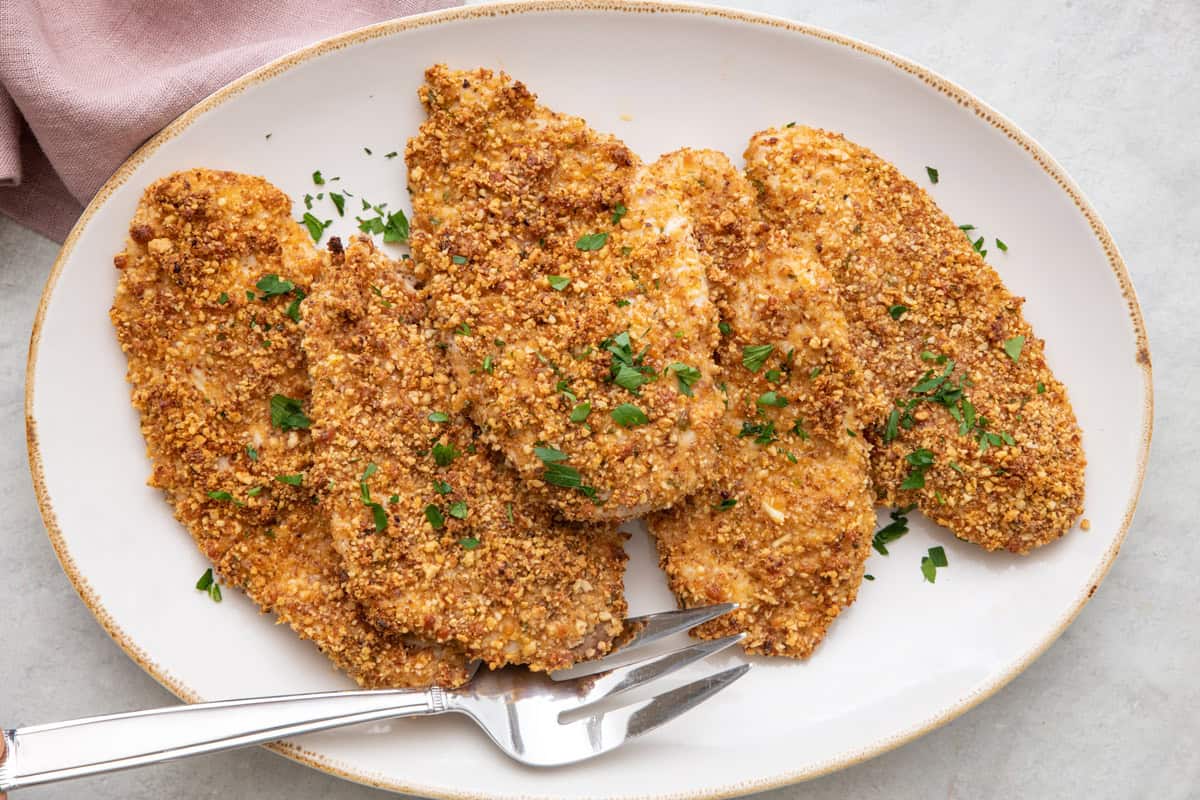 Baked almond crusted chicken breast cutlets on a serving platter.