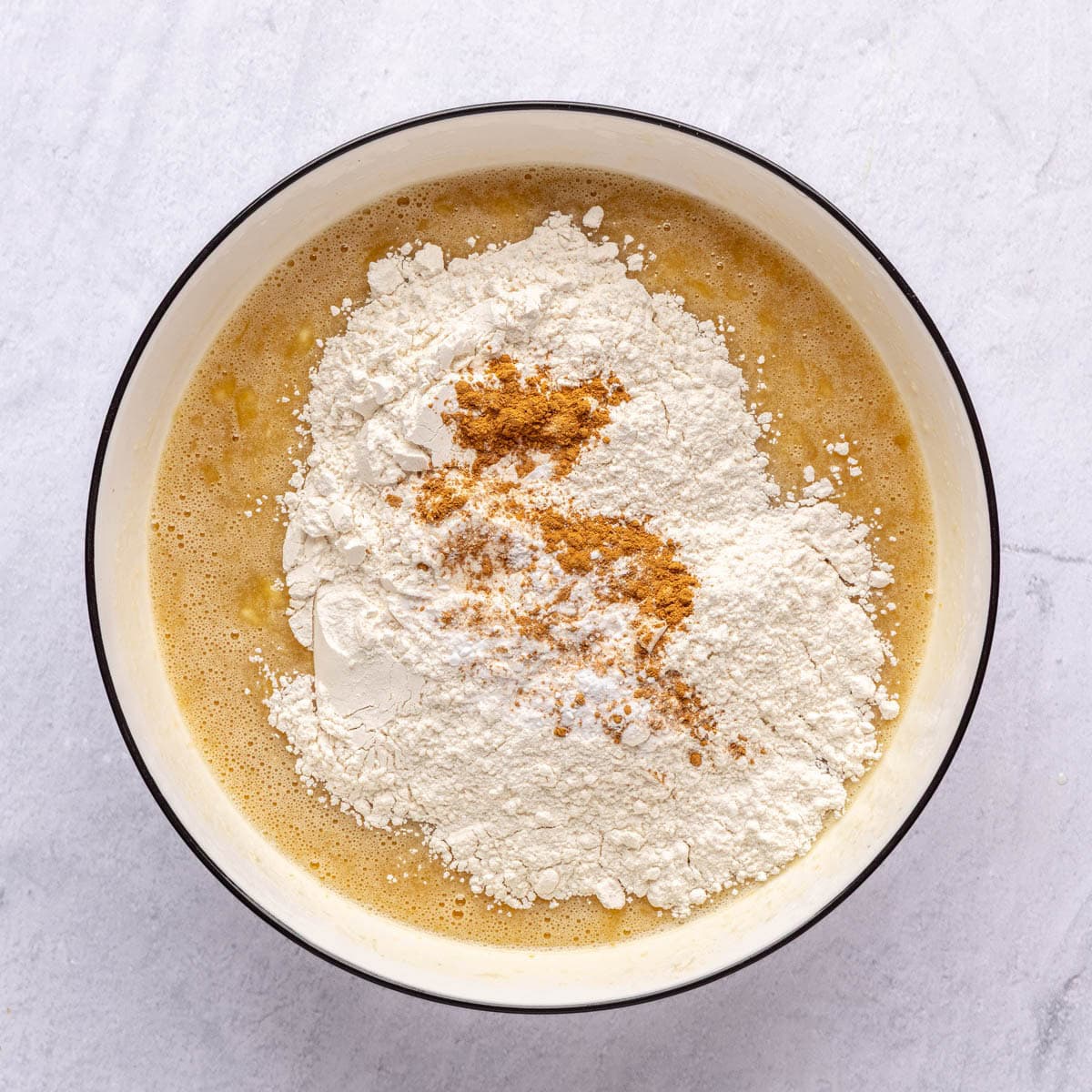 Dry ingredients added on top of banana mixture in a bowl before combining.