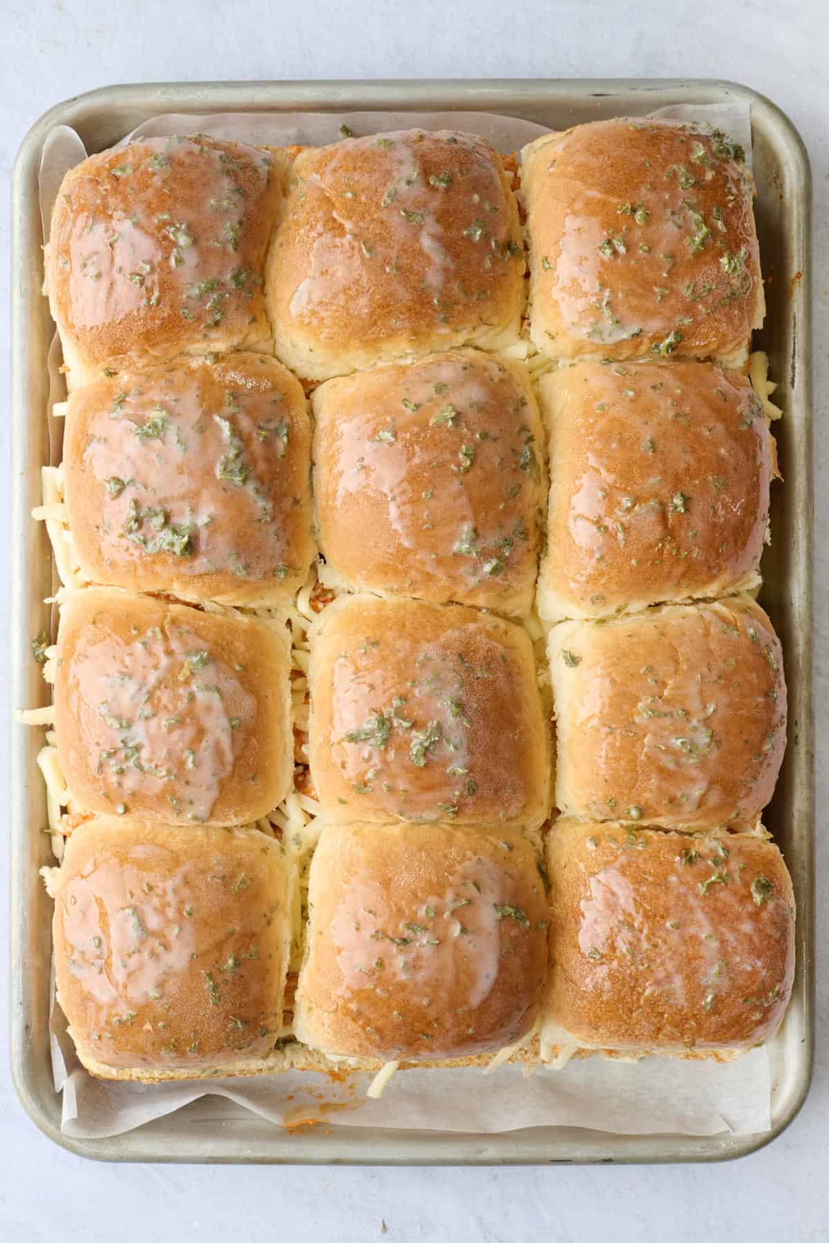 Slider buns added on top of chicken and cheese filling with melted butter brushed on top before baking.