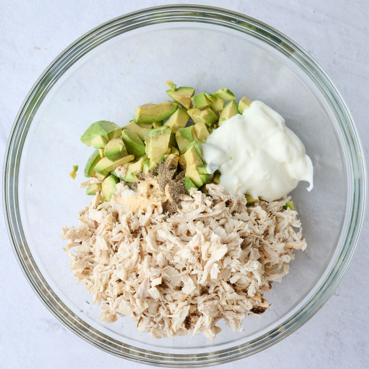 Shredded chicken, avocado, yogurt, lime juice and seasonings in a bowl before gently combining.