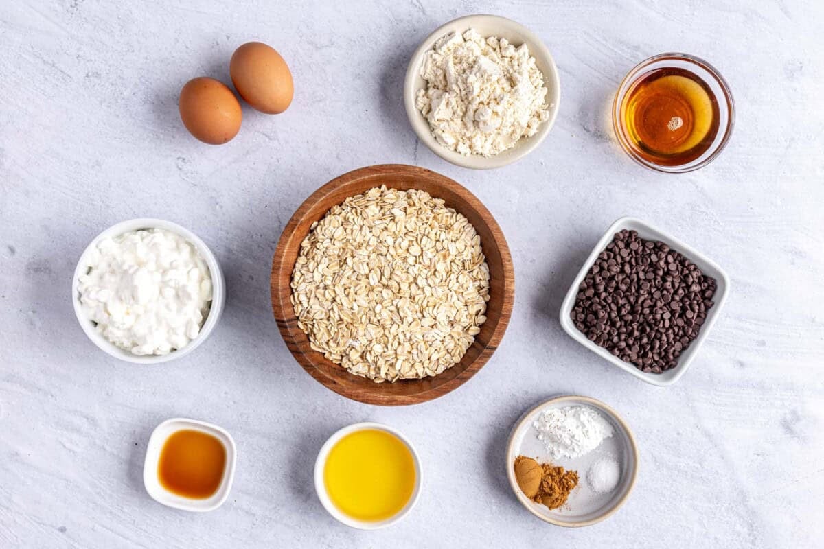 Ingredients for muffin recipe: cottage cheese, eggs, vanilla protein powder, maple syrup, oats, vanilla, oil, baking powder, cinnamon and salt.