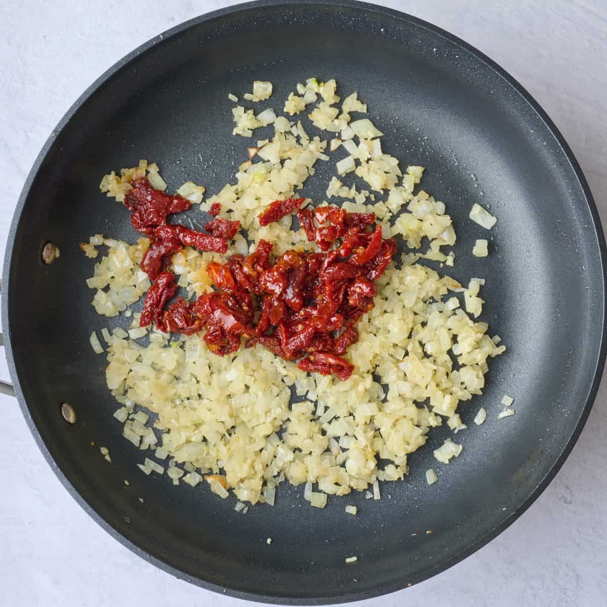 Cooked onions and garlic in pan with sun dried tomatoes added before combining.