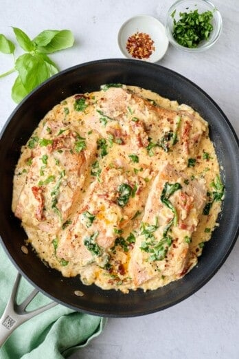 Best Tuscan salmon recipe made with sun dried tomatoes and spinach in a creamy sauce served in the pan.