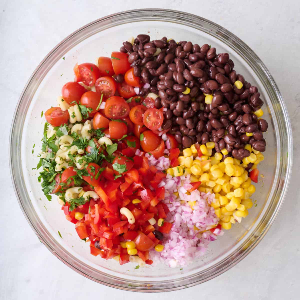 Chopped onion, red bell pepper, cilantro, tomatoes, corn and black beans added to pasta bowl before tossing.