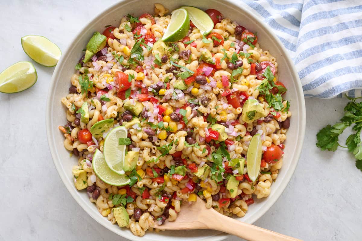 Easy bean pasta salad recipe in a serving bowl with lime wedges.